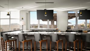 A modern kitchen with a large island, bar stools, and pendant lighting.