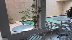 Un patio con piscina, sillas de metal y una mesa.