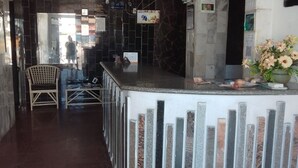 Un área de recepción con mostrador de mármol, una silla y un arreglo floral.