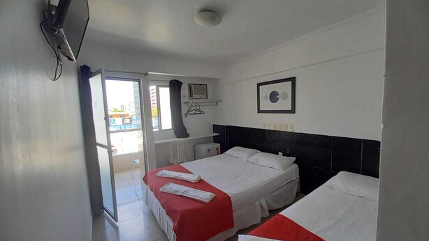 Habitación de hotel con dos camas, televisión, ventana y vista al exterior.