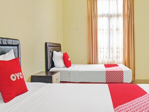 Una habitación de hotel con dos camas, una mesita de noche y una ventana con cortinas.