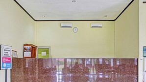 Un hall d’entrée avec un comptoir de réception en marbre, une horloge et un panneau d’affichage.