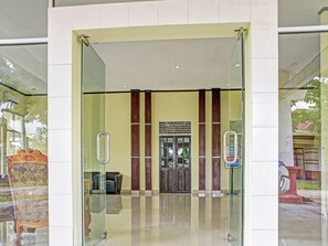Una entrada moderna a un edificio con puerta de cristal, mostrador de recepción y rótulo.