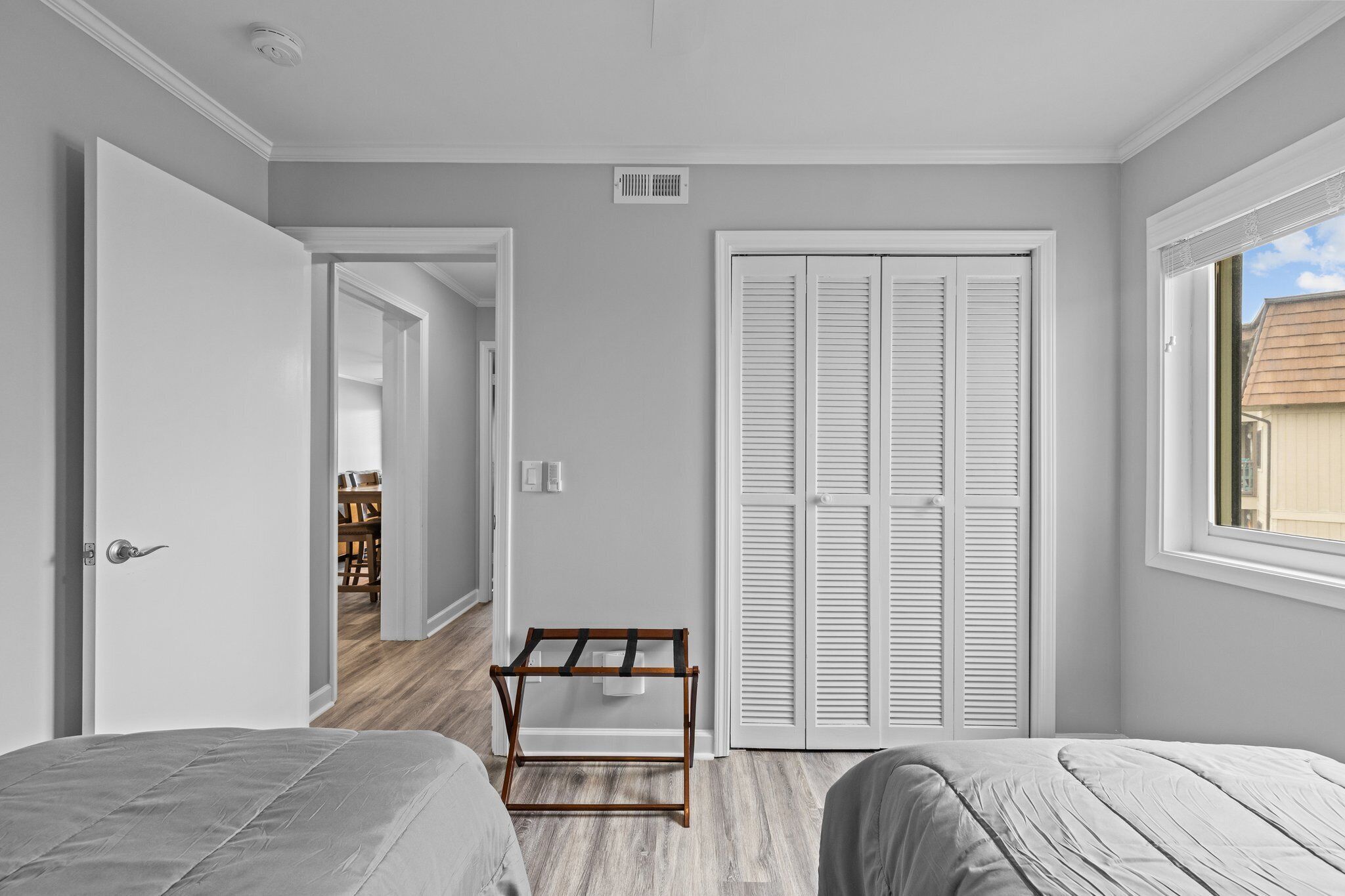 A bedroom with two beds, a wardrobe, and a window.