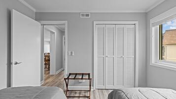 A bedroom with two beds, a wardrobe, and a window.