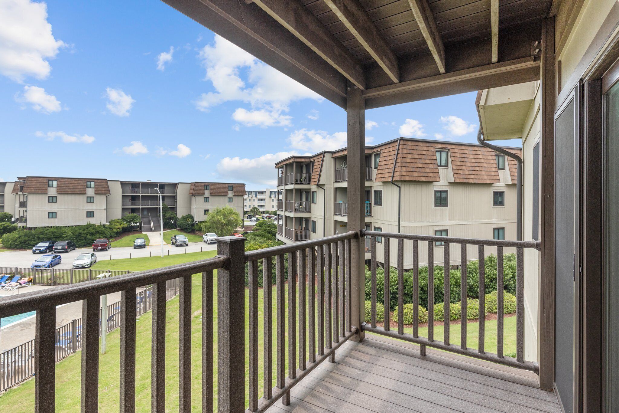 A balcony with a view of a residential complex, including multiple buildings and a parking area.