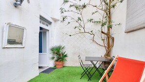 A small patio with artificial grass, a wooden chair, a table, and a potted plant. - La Suite 24 - Port St-Martin-de-Ré- Studio terrace (Saint-Martin-de-Ré)