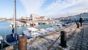 A marina with boats docked, a stone walkway, and buildings in the background. - La Suite 24 - Port St-Martin-de-Ré- Studio terrace (Saint-Martin-de-Ré)