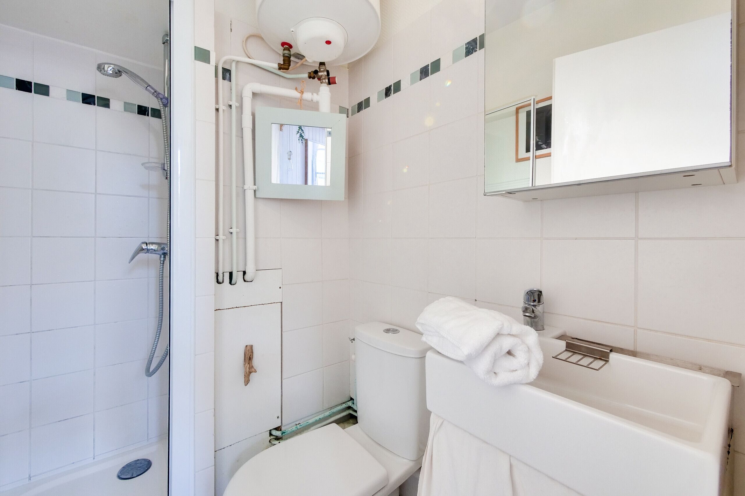 Une salle de bain équipée d’une douche, de toilettes, d’un lavabo et d’un miroir.