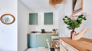A compact kitchen with teal cabinets, a wooden dining table, and a rustic decor piece. - La Suite 24 - Port St-Martin-de-Ré- Studio terrace (Saint-Martin-de-Ré)