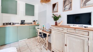 A compact kitchen with a dining area, a TV, and a hanging light fixture. - La Suite 24 - Port St-Martin-de-Ré- Studio terrace (Saint-Martin-de-Ré)