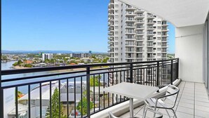 A balcony with a table and chairs, overlooking a river and a high-rise building. - Chevron Renaissance Private room Lvl16 (Surfers Paradise)