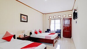 A hotel room with two beds, a TV, a desk, and a chair. - Collection O 90461 Graha Atmadja Syariah Guest House (Lembang)