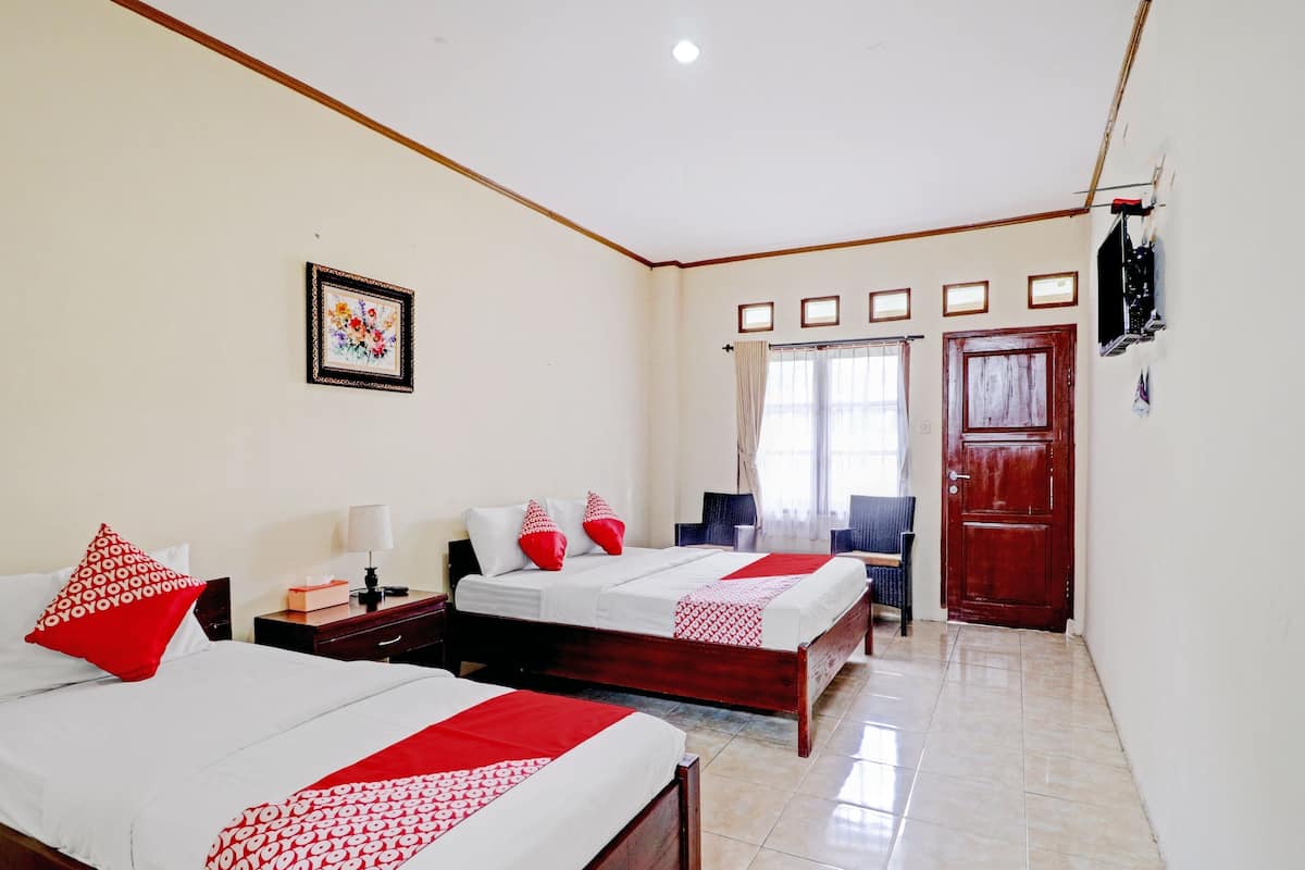 A hotel room with two beds, a TV, a desk, and a chair.