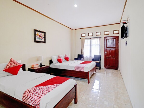 A hotel room with two beds, a TV, a desk, and a chair.