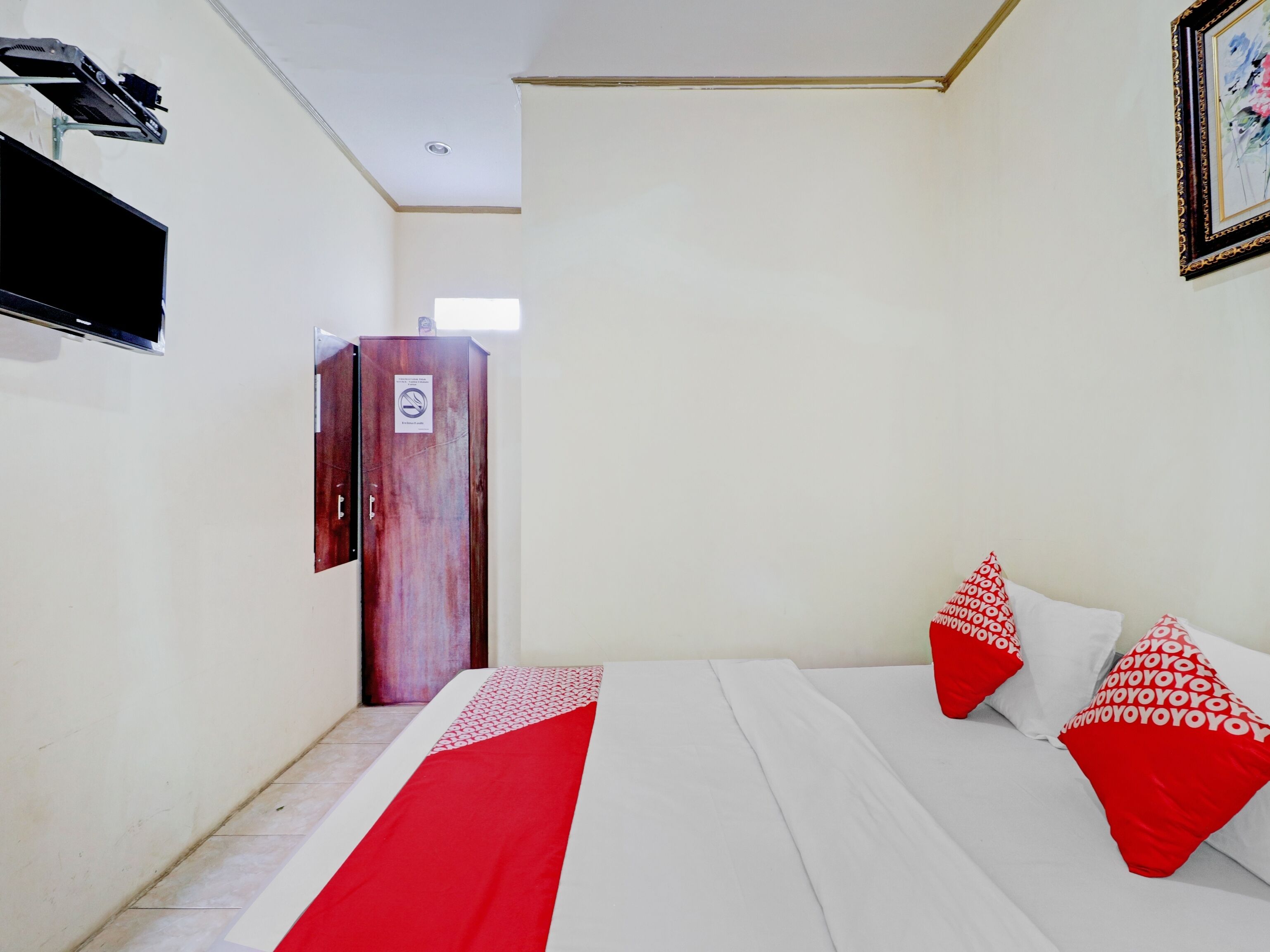 Une chambre d’hôtel avec un lit, des oreillers, une armoire, une télévision et une porte.