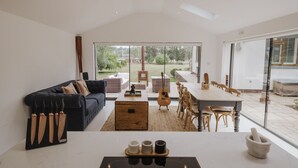Een moderne woonkamer met een bank, eettafel en keuken, met uitzicht op de tuin.
