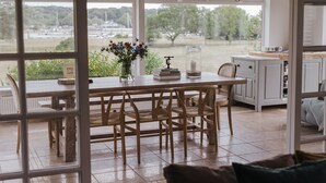 Een eethoek met een houten tafel, stoelen en een vaas met bloemen.