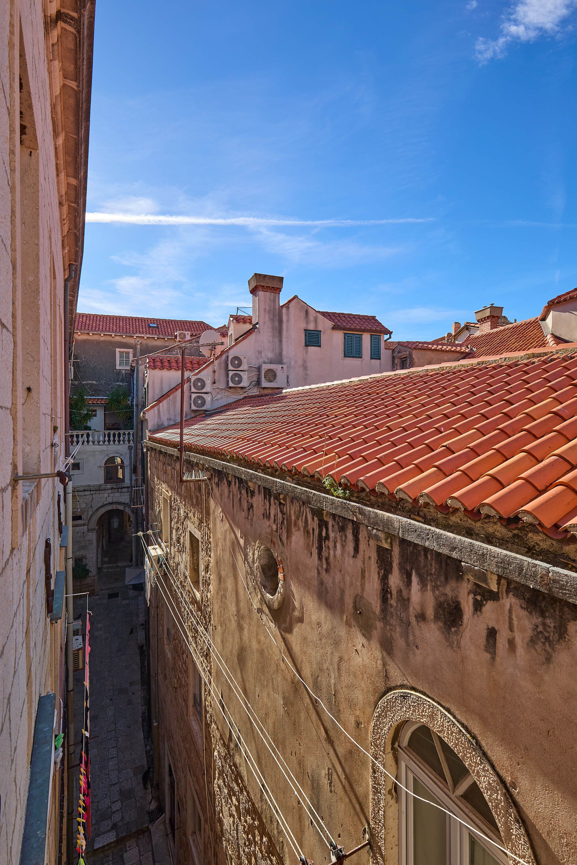 Una calle estrecha con edificios que tienen techos de tejas rojas y ventanas arqueadas.