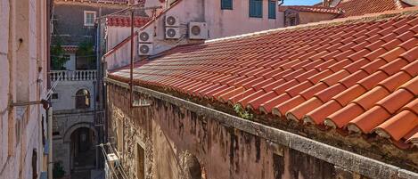 Una calle estrecha con edificios que tienen techos de tejas rojas y ventanas arqueadas.