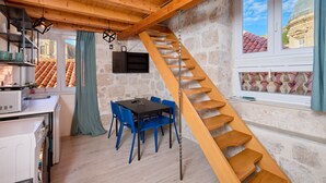 Una cocina moderna con comedor, una escalera de madera y una pared de piedra.