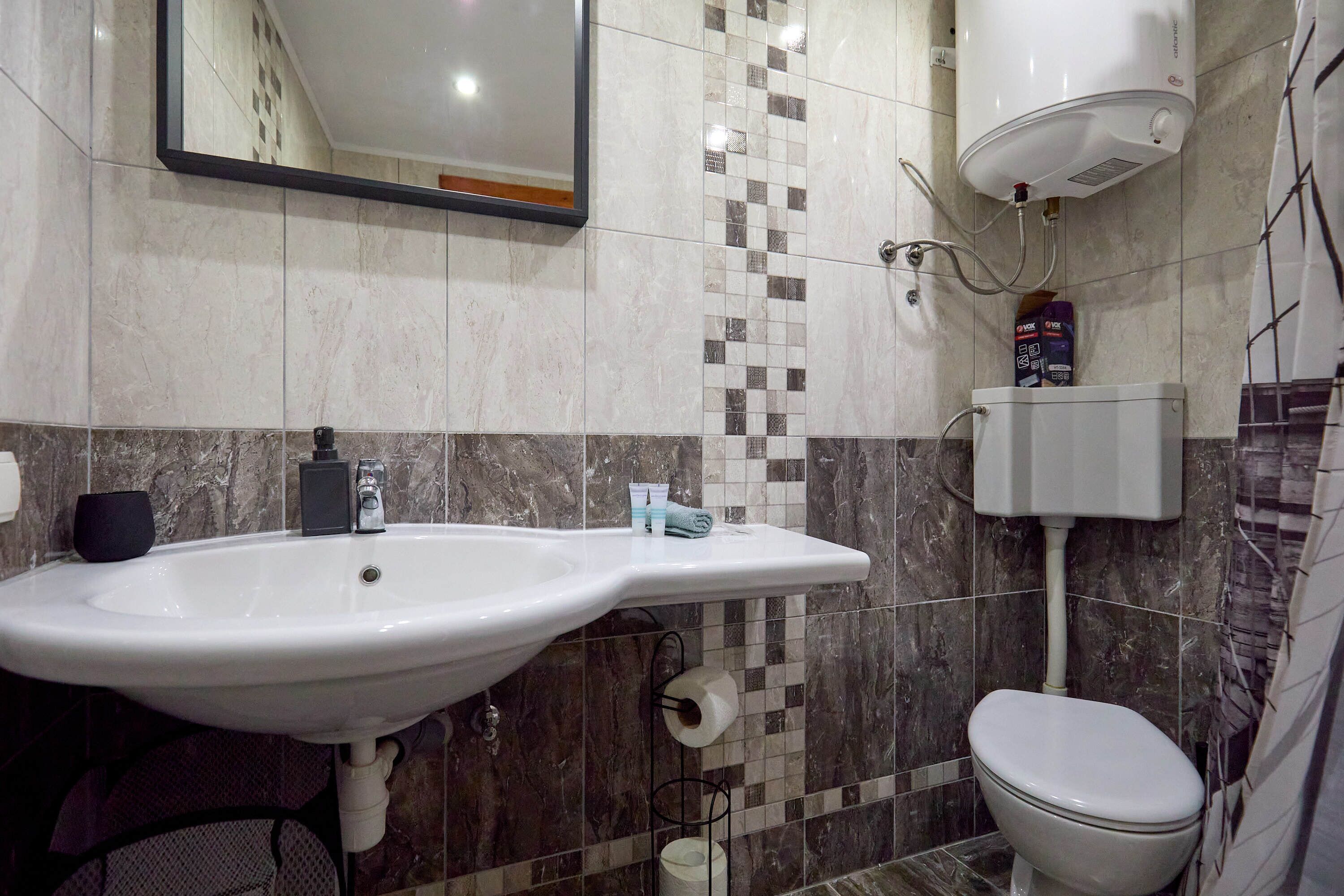 A bathroom with a white sink, toilet, and a mirror above the sink.