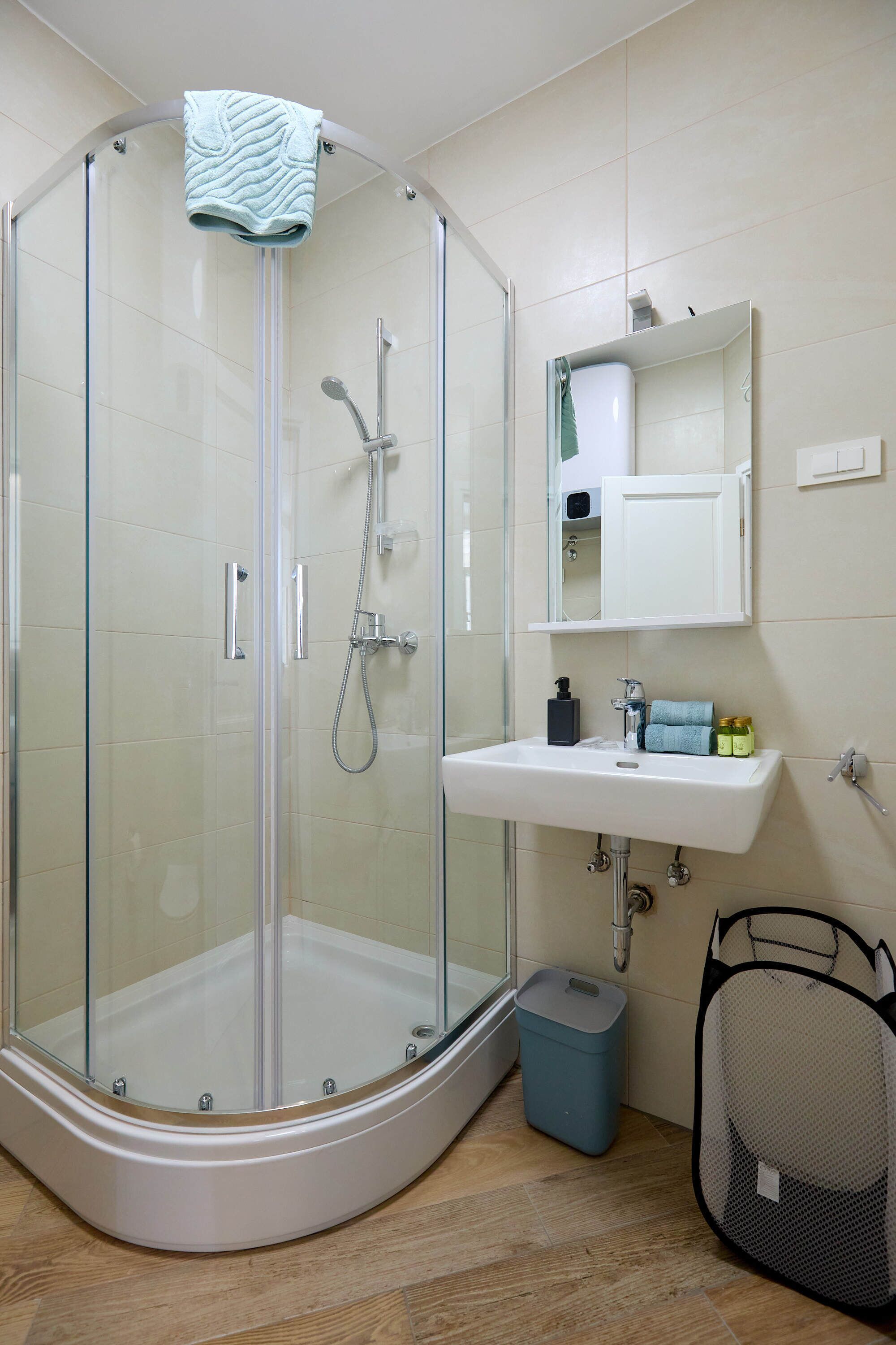 A modern bathroom with a glass-enclosed shower, a white sink, and a mirror above it.