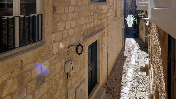 Un estrecho callejón con edificios de piedra, un ventanal visible y una puerta.