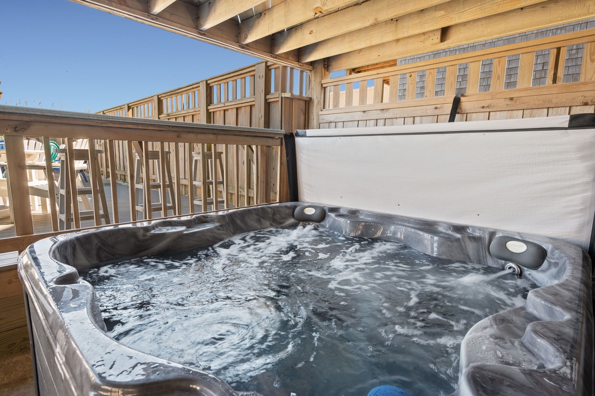 A hot tub with a wooden deck and railings.