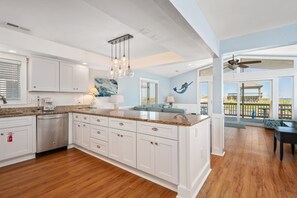 A spacious kitchen with white cabinetry, a granite countertop, and a large island.