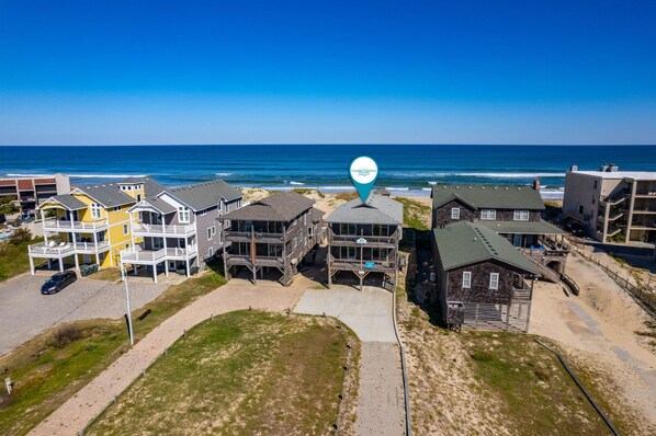 A coastal residential area with a mix of modern and traditional houses, a clear view of the ocean, and a location marker indicating 'County Campus'.