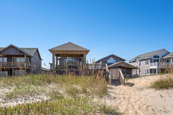 A beachfront property with multiple wooden houses, a covered porch, and a sandy beach.