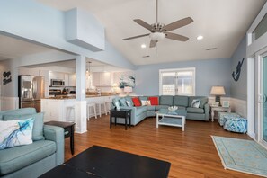 A spacious living room with a sectional sofa, a coffee table, and a ceiling fan.