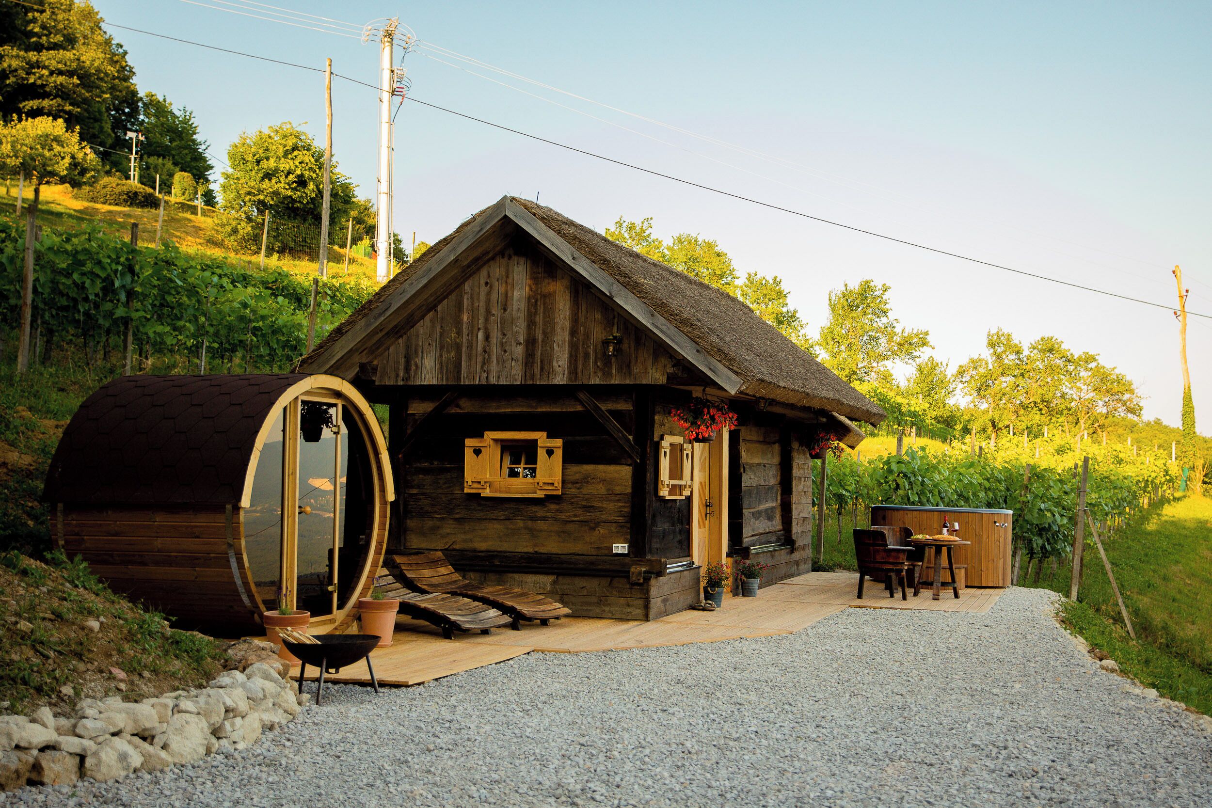 Una cabaña rústica de madera con techo de paja, un ventanal redondo y una terraza de madera.