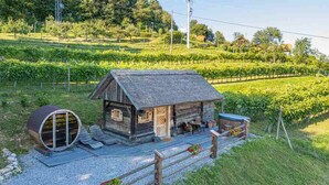 A rustic cabin with a thatched roof, a wooden porch, and a barrel. - Glamping Paradise Škatlar (Novo Mesto)