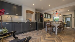 Een moderne keuken met donkere kastjes, een centraal eiland en een eethoek met houten stoelen.