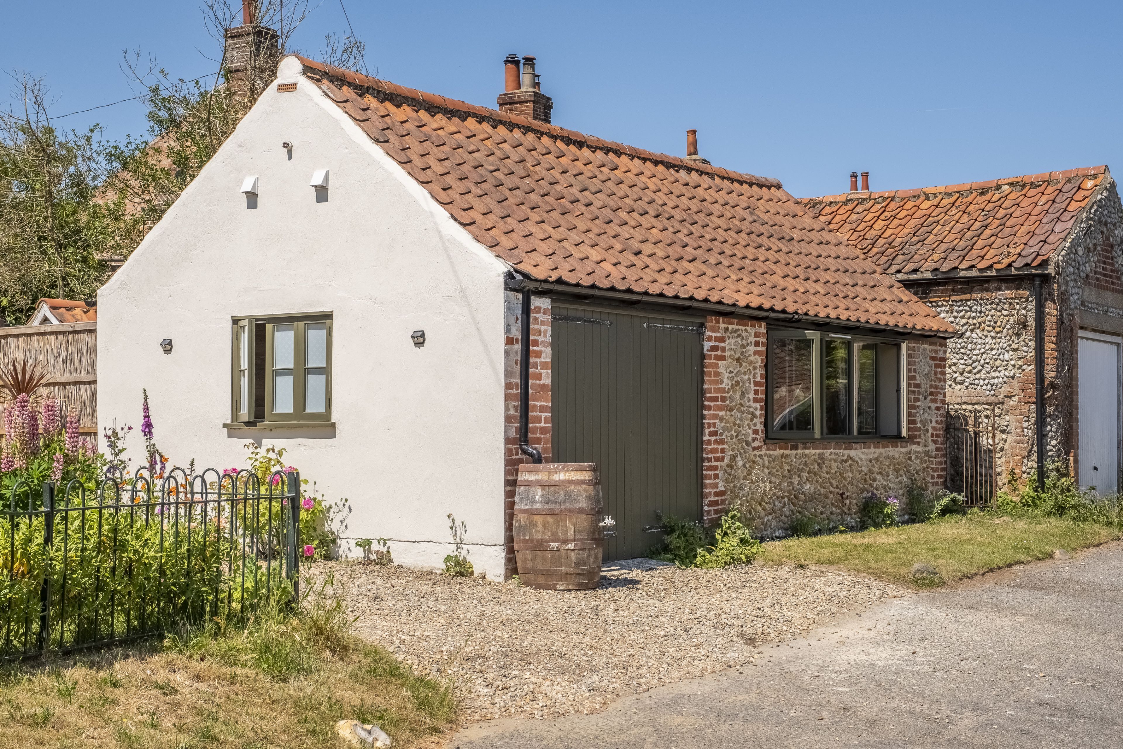 A white, single-story house with a brown tiled roof and a stone exterior.