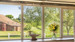 Ein Fenster mit Blick auf ein Ziegelgebäude, eine weiße Heizung und eine Vase mit Blumen.