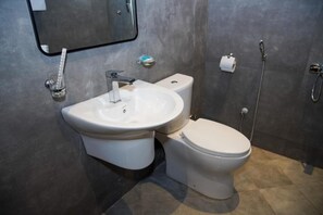 Ein modernes Badezimmer mit Waschbecken, Toilette und Dusche in Weiß.