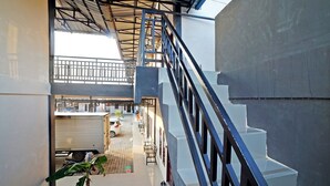 A multi-level building with a staircase, a covered outdoor area, and a vehicle parked outside. - OYO 90618 Hanania House Syariah (Langsa)