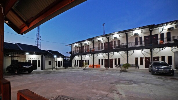 A two-story building with multiple balconies and a parking area in front. - OYO 90618 Hanania House Syariah (Langsa)
