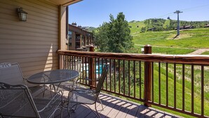 A balcony with metal chairs and a table, overlooking a pool and a mountainous landscape. - AN124 | Antlers Steamboat | Close to Base | A/C | Ski In/Out (Steamboat Springs)
