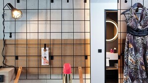 A room with a grid wall, a hanging lamp, a mirror, and a dress on a hanger. - Moxy Vienna City East (Vienna)