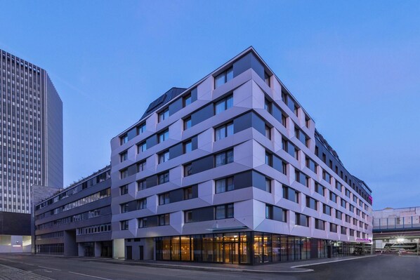 Un hôtel moderne à plusieurs étages, doté d’une façade aux lignes géométriques, de grandes fenêtres et d’un toit plat.