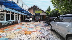 Un espace de stationnement avec un sol en mosaïque, un bâtiment portant l’inscription « OYO LIFE », et des voitures garées.