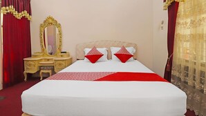 Une chambre d’hôtel avec un grand lit, une table de chevet, un miroir et des rideaux rouges.