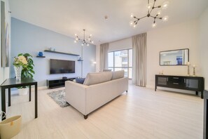 A modern living room with a sofa, TV, and a large window.
