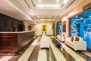 Eine moderne Lobby mit Empfangstresen, Sitzgelegenheiten und großen Fenstern mit Blick auf eine Parkgarage.