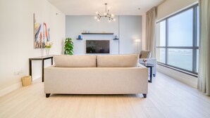 A modern living room with a sofa, TV, and large windows.
