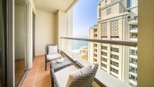 A balcony with a table, chairs, and a view of high-rise buildings.